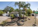 Residential home with tropical foliage, gravel driveway, and white exterior at 1702 E Knollwood St, Tampa, FL 33610