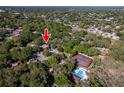 Aerial view shows the property surrounded by lush greenery, plus a pool and tennis courts at 2627 2Nd Ct, Palm Harbor, FL 34684