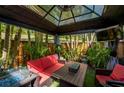 Inviting gazebo with cozy seating, mounted TV, and a unique fire pit table with tropical plants at 2627 2Nd Ct, Palm Harbor, FL 34684