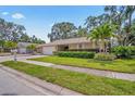 Well-manicured front yard and exterior of home featuring a charming single-story design and lush landscaping at 5600 Bay Pines Lakes Blvd, St Petersburg, FL 33708