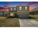 Charming two-story home with a two car garage during a colorful sunset at 6967 Silverado Ranch Blvd, Zephyrhills, FL 33541
