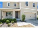 Close up of the front door with tan stucco and a two car garage on a sunny day at 6967 Silverado Ranch Blvd, Zephyrhills, FL 33541