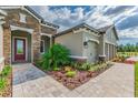 Beautiful home exterior showcasing stone accents, lush landscaping, a red door, and a three-car garage at 712 Estates Blvd, Tarpon Springs, FL 34689