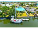 Waterfront home with a private dock, boat, and mature landscaping, featuring a striking blue roof and lush lawn at 732 Kingston Ct, Apollo Beach, FL 33572