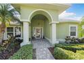 Inviting front entrance featuring an arched doorway with white columns and manicured landscaping at 826 Christina Cir, Oldsmar, FL 34677