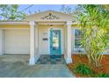 Inviting entryway with a decorative blue door, manicured landscaping, and covered entrance at 9265 Treasure Ln Ne, St Petersburg, FL 33702