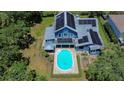 Aerial view of a home with a pool and solar panels on the roof surrounded by lush greenery, perfect for energy efficiency at 9303 Alice Ln, Riverview, FL 33578