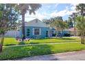 Landscaped front yard with mature trees, a lush lawn, and a well-maintained blue home with white trim at 16605 Round Oak Dr, Tampa, FL 33618