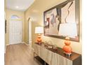 Welcoming foyer with wood floors, stylish console table, lamps and decorative artwork at 16802 Fairbolt Way, Odessa, FL 33556