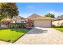 Single-story home featuring manicured landscaping and a brick-paved driveway at 16802 Fairbolt Way, Odessa, FL 33556