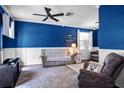 Cozy living room featuring blue accent walls, white wainscoting, and comfortable seating at 1755 Open Field Loop, Brandon, FL 33510