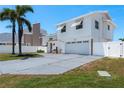 A two-story home with a white exterior, red roof, two-car garage, and a well-manicured lawn at 2202 Donato Dr, Belleair Beach, FL 33786