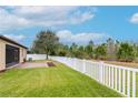 Large grassy backyard with a brick patio, a white picket fence, and view of trees at 3914 Round Table Ct, Land O Lakes, FL 34638