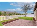 Expansive backyard with a brick patio, green grass, and a white picket fence at 3914 Round Table Ct, Land O Lakes, FL 34638