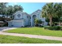 Charming two-story home with lush green lawn, landscaped yard, and a light blue exterior at 4063 Ligustrum Dr, Palm Harbor, FL 34685