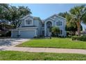 Charming two-story home with lush green lawn, landscaped yard, and a light blue exterior at 4063 Ligustrum Dr, Palm Harbor, FL 34685