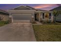 Charming single-story home with well-maintained lawn and a two-car garage at sunset at 5464 Flint Hills Dr, Wimauma, FL 33598