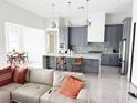 Open-concept kitchen with gray cabinets, stainless steel appliances, an island, and pendant lighting at 5717 Tybee Island Dr, Apollo Beach, FL 33572