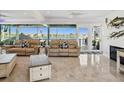 Bright living room with leather sofas, tile floors, and expansive windows offering stunning waterfront views at 5820 Balao S Way, St Pete Beach, FL 33706