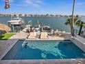 Beautiful waterfront home featuring a private pool, boat dock with lifts, and outdoor dining area at 5820 Balao S Way, St Pete Beach, FL 33706