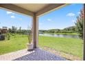 View from covered brick patio to green lawn, pond, and fence beyond at 9309 Tradewater Oaks Ct, Riverview, FL 33578