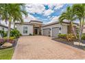 Beautiful home exterior featuring a three-car garage, brick driveway, and lush landscaping at 13208 Malachite Dr, Bradenton, FL 34211