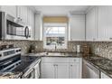 Bright kitchen features granite countertops, white cabinets, stainless steel appliances, and modern tile backsplash at 13696 Orange Sunset Dr, Tampa, FL 33618