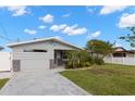 View of a gray single-story home with palm trees and manicured lawn, enhanced by a dolphin sculpture at 13704 Evelane Dr, Hudson, FL 34667