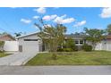 Single-story home with gray siding, well-maintained lawn and driveway, complemented by mature trees and landscaping at 13704 Evelane Dr, Hudson, FL 34667