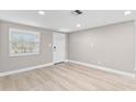 Bright living room with light wood floors, a front door with decorative glass, and large window at 13704 Evelane Dr, Hudson, FL 34667