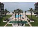 View of the community pool and shuffleboard area with palm trees and beach in the background at 18304 Gulf Blvd # 309, Redington Shores, FL 33708