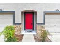 Close-up of a vibrant red front door framed by stone accents, flanked by garage doors at 2547 Lexington Oak Dr, Brandon, FL 33511