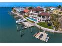 Waterfront property featuring a private boat dock, pool, outdoor lounging, and lush landscaping on a sunny day at 5939 Bayview S Cir, Gulfport, FL 33707