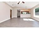 Bright living room with neutral walls, vaulted ceiling, ceiling fan, luxury vinyl plank flooring, and pass through to kitchen at 8561 Deer Chase Dr, Riverview, FL 33578