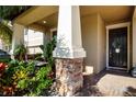 Inviting front porch featuring stone accents, lush plants, and a cozy swing for relaxing outdoors at 13651 Ashlar Slate Pl, Riverview, FL 33579