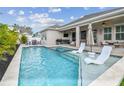 Inviting backyard pool and spa area with lounge chairs and covered patio at 1499 Gopher Loop, Tarpon Springs, FL 34689