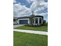Charming single-story home with a blue garage door, landscaped yard, and sidewalk at 17116 Moonflower Dr, Venice, FL 34293