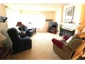 Cozy living room featuring carpeted floors, recliners, and a charming fireplace at 2101 Sunset Point Rd # 205, Clearwater, FL 33765
