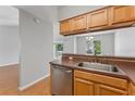 Modern kitchen area featuring wooden cabinetry, stainless steel dishwasher, and a view to the living room at 581 Oceanview Ave, Palm Harbor, FL 34683
