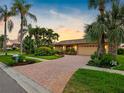 Charming home exterior with a brick driveway, lush landscaping, and a well-maintained lawn at 5816 Dory Way, Tampa, FL 33615
