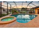 Relaxing pool and spa area inside a screened enclosure with a view of the waterfront and lush landscaping at 5816 Dory Way, Tampa, FL 33615