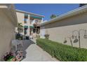 Charming condo with a private walkway, featuring lush landscaping, white outdoor seating, and tranquil garden decor at 6330 99Th N Way # 14F, St Petersburg, FL 33708