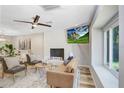 Cozy living room featuring a decorative white brick fireplace, ceiling fan, and large window at 7208 N Ola Ave, Tampa, FL 33604