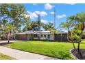 Single-story home features well-maintained landscaping, palm trees, and a neutral color scheme at 820 Hickory Ln, Palm Harbor, FL 34683