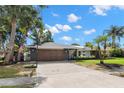 Charming single-story home boasts a well-maintained lawn, palm trees, and a neutral color scheme at 820 Hickory Ln, Palm Harbor, FL 34683