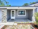 Home exterior highlighting the front door, gray siding, stone accent, and a small, well-tended garden area at 10931 110Th Ave, Seminole, FL 33778