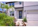 Welcoming front entrance with a blue door, lush landscaping and a two-car garage at 12905 Brookside Moss Dr, Riverview, FL 33579