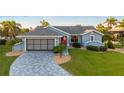 Well-maintained blue single-story home with a red front door, manicured lawn, and a patterned concrete driveway at 220 Singapore Rd, Punta Gorda, FL 33950