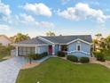 Charming blue single-story home with a red front door, manicured lawn, and a patterned concrete driveway at 220 Singapore Rd, Punta Gorda, FL 33950