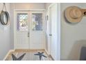 Bright foyer featuring a decorative front door with glass panels, and a starfish rug over light hardwood flooring at 220 Singapore Rd, Punta Gorda, FL 33950